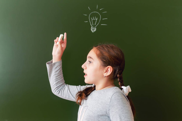 A schoolgirl at the blackboard was able to find a solution to the problem. inspiration. the idea came - Zdjęcie, obraz