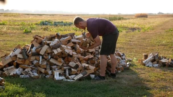 Een man draagt brandhout met zijn handen in het dorp - Video