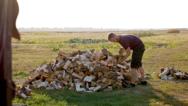 Człowiek nosi drewno opałowe z rękami w wiosce - Materiał filmowy, wideo