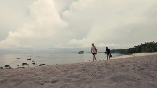 Pár turista hátizsákos séta a fehér homokos tengerparton egy gyönyörű szigeten - Felvétel, videó