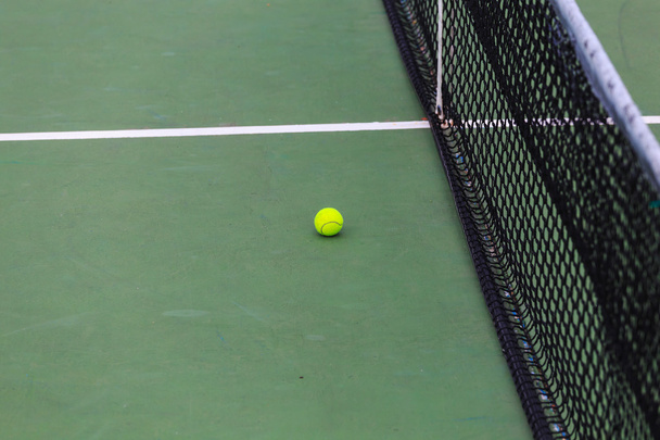 tennisbal op de rechter close-up met net op de achtergrond - Foto, afbeelding