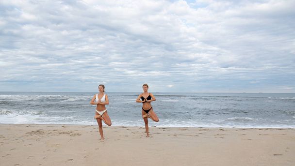 Young women practicing yoga on the beach - Photo, Image