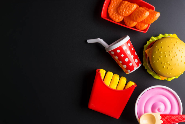 Plastic burger, French fries Fast food on black background. Chil - 写真・画像