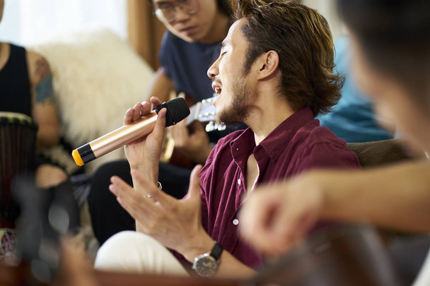nuoret aasialaiset aikuiset laulavat ja soittavat soittimia
 - Valokuva, kuva