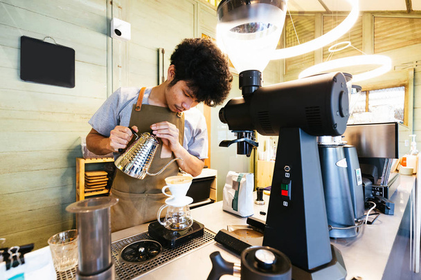 Barista making pour-over coffee with alternative method called Dripping. Coffee grinder, coffee stand and pour-over on a wooden table. - Φωτογραφία, εικόνα