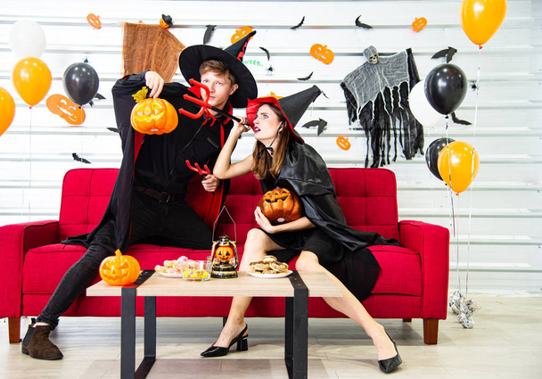 Happy Halloween party concept. Young man and woman wearing the fantacy as vampires, witch or ghost celebrate the halloween festival in the room decorated with balloon, bat and pumpkin. - Photo, Image