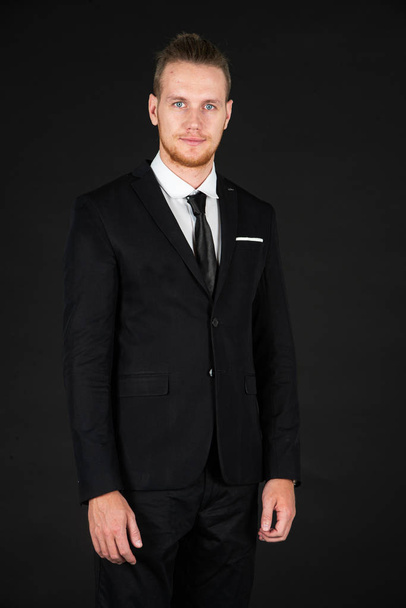Portrait of smart, handsome and confident business man in black suit standing on isolated black background. - Foto, immagini