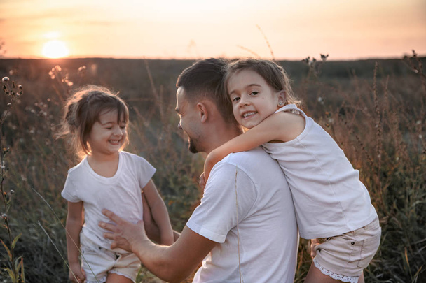 Папа и его дочери в поле на закате
 . - Фото, изображение