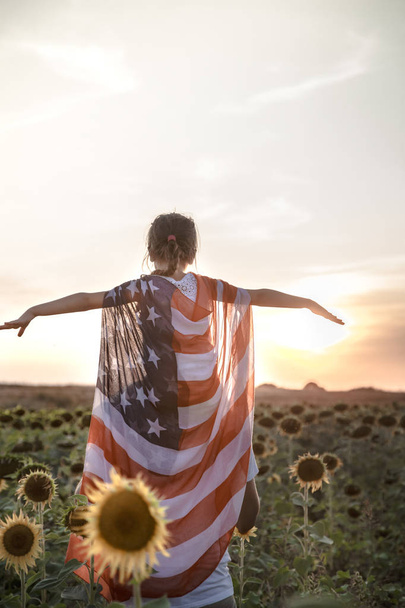 a girl holds an American flag at sunset . - Photo, Image