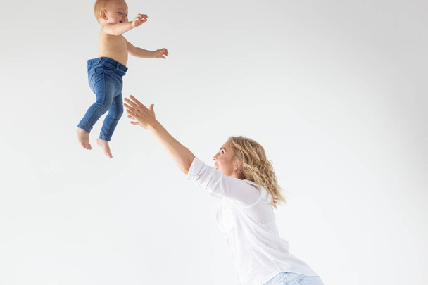 Mère célibataire, concept de maternité et de bébé - Mère joyeuse s'amusant avec sa petite fille en studio, isolée sur fond blanc
 - Photo, image