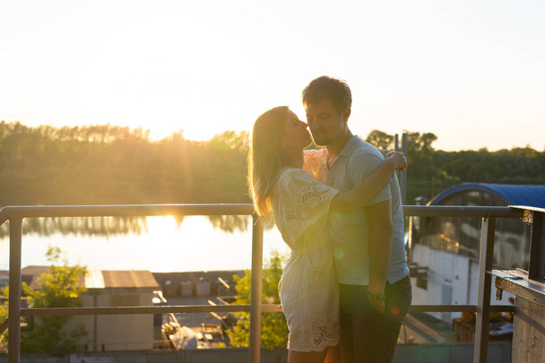Wonderful young couple hug and enjoy life together with natural outdoor leisure activity lifestyle on nature and the sunset in backlight. - Photo, Image