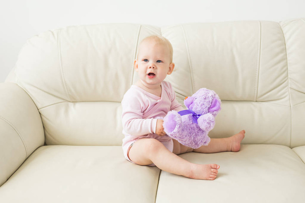 Çocuklar, bebek ve çocukluk konsepti - Güzel sevimli yumuşak bebek kanepede oturan - Fotoğraf, Görsel