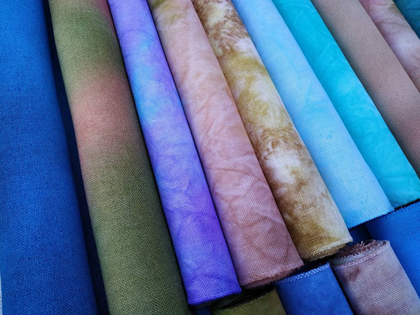 Rollos de telas de colores. Tejido teñido para coser. Tejido de punto de cruz
 - Foto, Imagen
