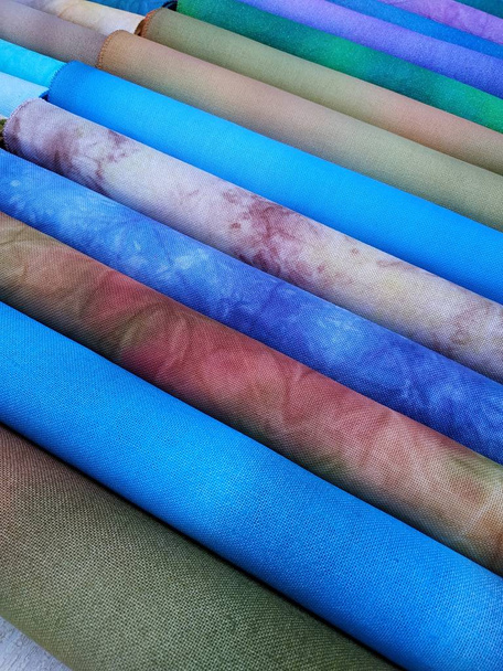 Rolls of colorful fabrics. Dyed fabric for sewing. Cross stitch fabric - Photo, Image