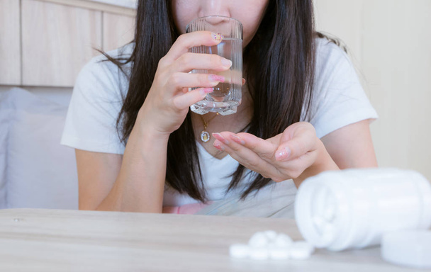 Mulher da medicina da gripe infectada com frio a droga é colocada sobre a mesa e um copo de água
. - Foto, Imagem