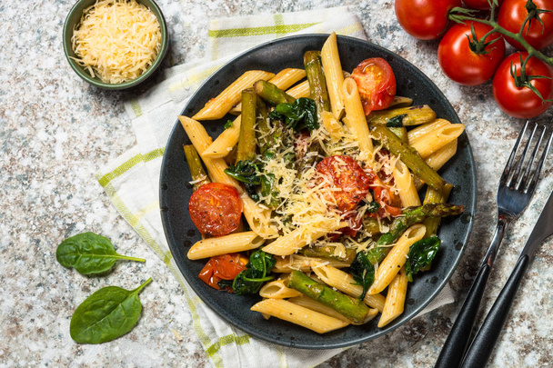 Penne de pasta vegana con espinacas, espárragos y tomate
. - Foto, imagen