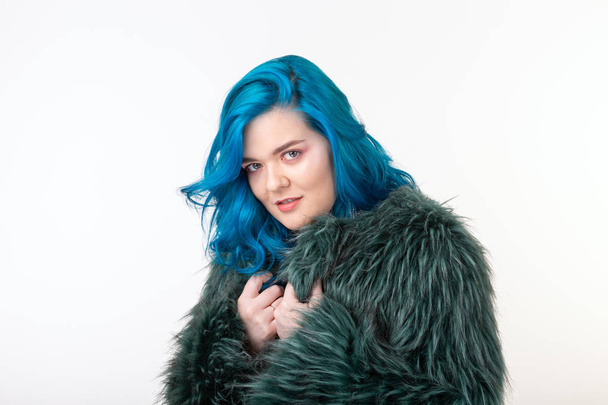 Animal protection, fashion and hair concept - beautiful girl with blue hair dressed in artificial fur coat standing on white background - Photo, Image
