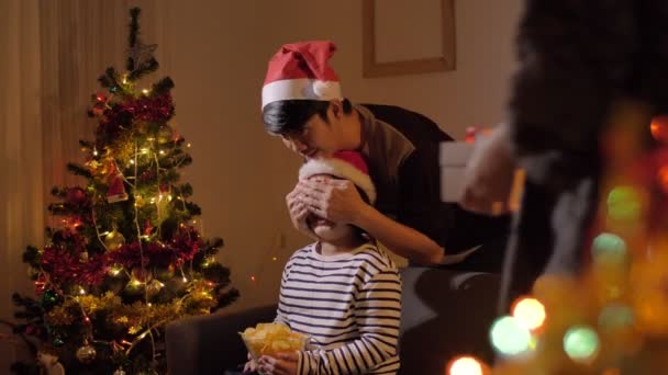 Christmas gift surprise Asian child receiving present with family celebrating festive holiday at home - Felvétel, videó