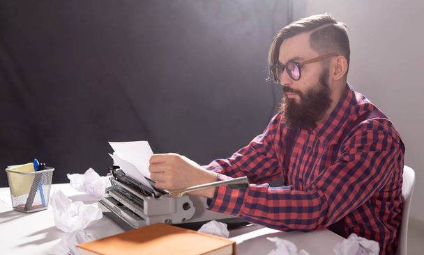 Menschen und Technologie-Konzept - Welttag des Schriftstellers, gutaussehender Mann mit Brille, im karierten Hemd, auf Schreibmaschine arbeitend - Foto, Bild
