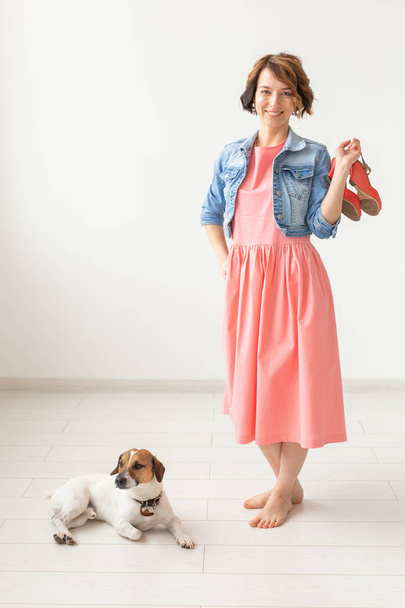 clothing designer, people, pet concept - young woman in dress and jeans jacket with jack russell - Photo, Image