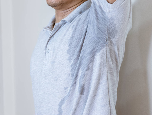 Ο άνθρωπος με λεκέ από ιδρώτα στα ρούχα, χρησιμοποιώντας αποσμητικό - Φωτογραφία, εικόνα