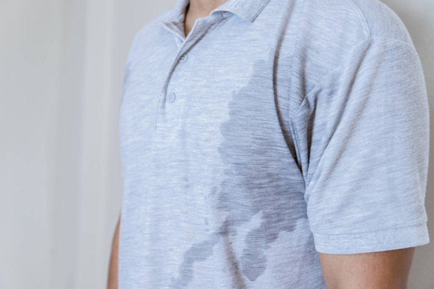 Man met zweet vlek op kleren tegen, met behulp van deodorant - Foto, afbeelding