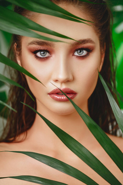 Portrait of young and beautiful woman in tropical leaves. - Fotoğraf, Görsel
