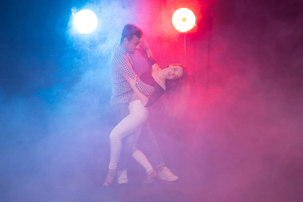 Социальный танец, кизомба, сальса и семба концепция - молодая красивая пара танцующая бачата или сальса в темноте
 - Фото, изображение