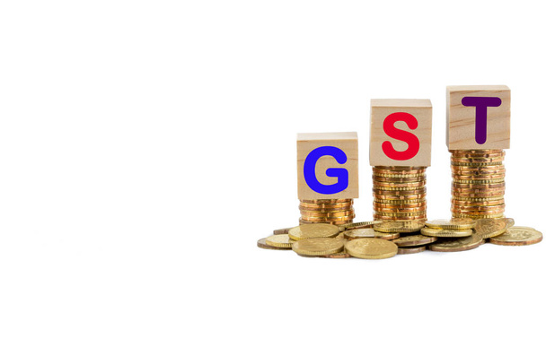 GST nebo daňový koncept s barevným dřevěným blokem a skládané mince na bílém pozadí - Fotografie, Obrázek