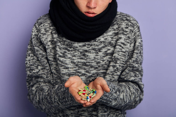 A man is holding a lot of different colorful pills in both his hands - 写真・画像