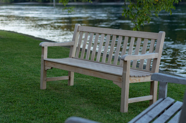 Twee houten banken op de voorgrond op de oever van de rivier bij zonsondergang in de herfst. - Foto, afbeelding