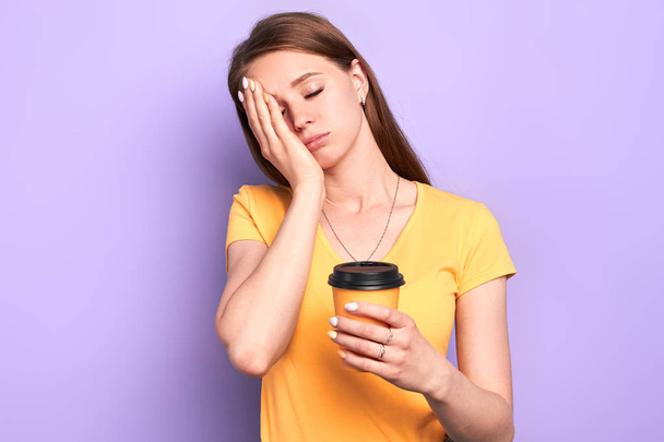Slaperige vrouwelijke student die koffie te gaan houdt, staand met gesloten ogen - Foto, afbeelding
