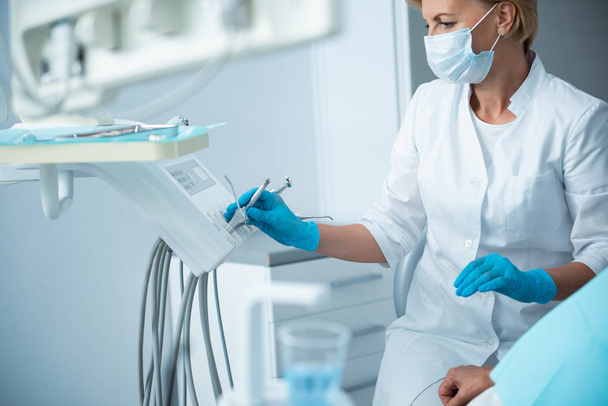 Female stomatologist in sterile gloves holding dentist instrument - Foto, Bild