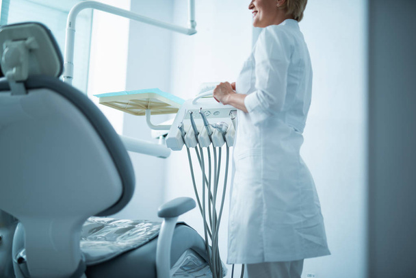 Female doctor is standing near dental chair - Фото, зображення