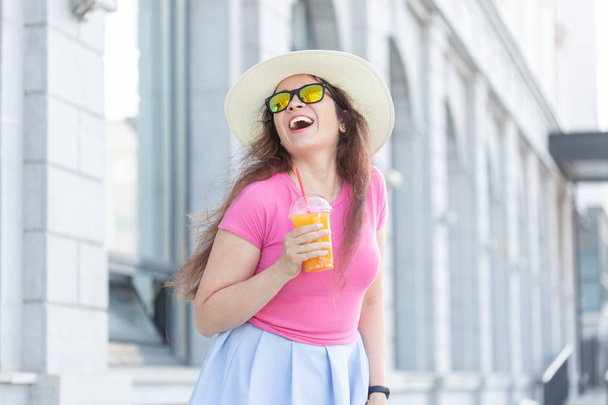 暖かい夏の日に街を歩く帽子と眼鏡をかけた美しいスタイリッシュな若い女性のクローズアップポートレート。幸せなポジティブな人々の概念. - 写真・画像