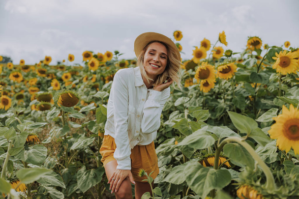 Young pretty lady spending time in sunflower field in summer - Foto, Imagen