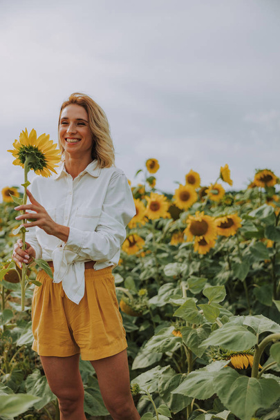 Happy young lady taking photo with bright sunflower in field in summer - Foto, Bild