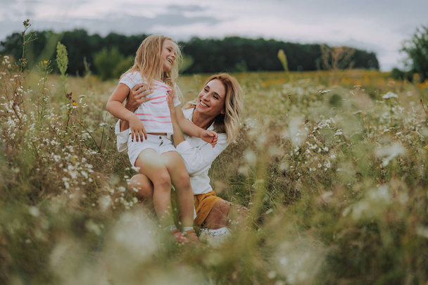 Happy lady hugging her small daughter in field - Photo, image
