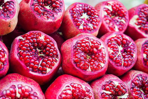 Background of fresh ripe pomegranates with incision on the counter in the street market. - Photo, Image