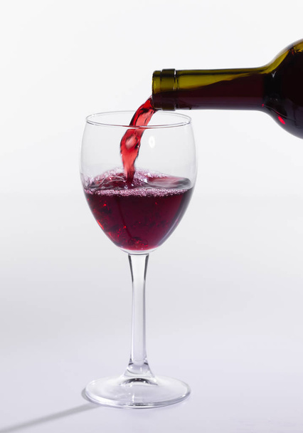 Červené víno z láhve do velkého skla na bílém - Fotografie, Obrázek