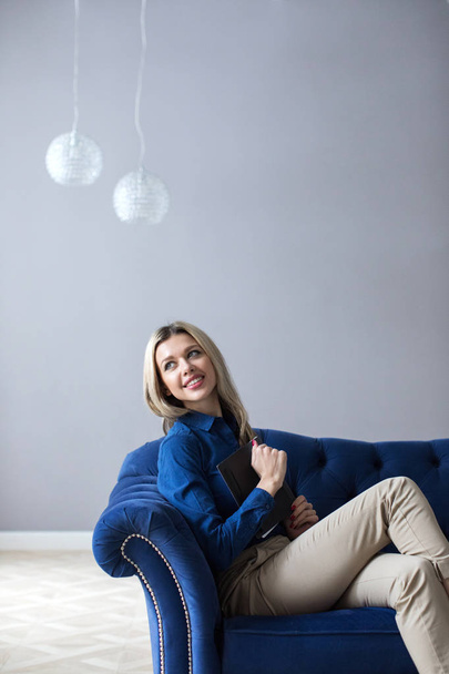 Portrait of a smiling blonde woman in an armchair. - Foto, Bild