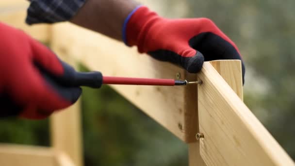 Взрослый плотник с отвёрткой прикручивает винт к доскам деревянного забора. Домашняя работа, сделай это сам. Видеозапись
. - Кадры, видео