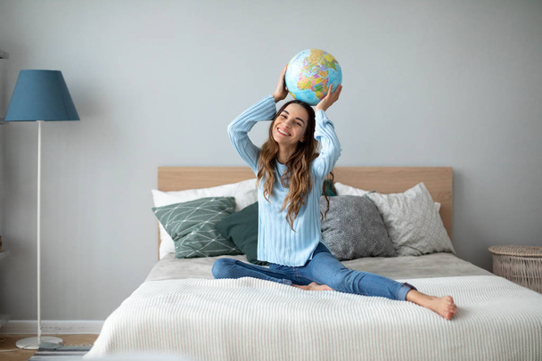 Happy woman with globe model of the world at home. - Фото, изображение