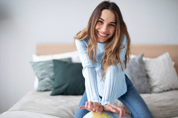 Joyful smiling woman indoors with a globe looking at the camera.  - Foto, Imagem