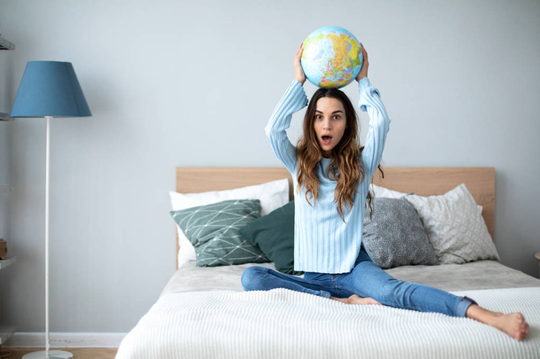 Young woman with globe model of the world at home. - Valokuva, kuva