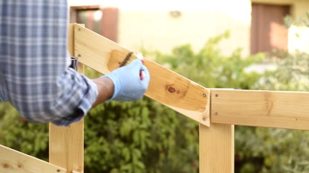Felnőtt kézműves Asztalos az ecset festés a táblák egy fából készült kerítés. Házimwork, csináld magad. Felvétel. - Felvétel, videó