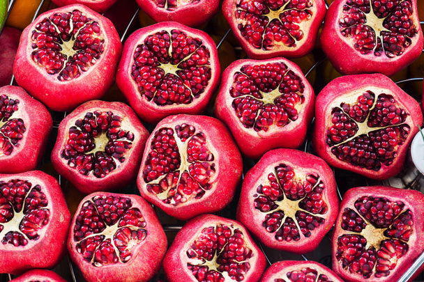 Background of fresh ripe pomegranates with incision on the counter in the street market. - Photo, Image