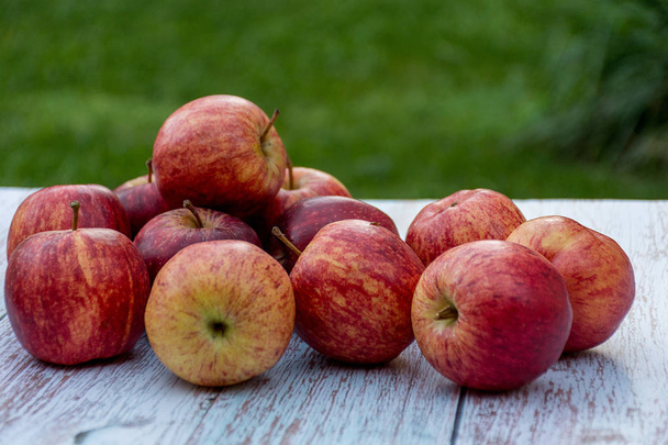 Органические спелые яблоки на деревянном столе в саду. Готовить ингредиенты. Урожай
. - Фото, изображение