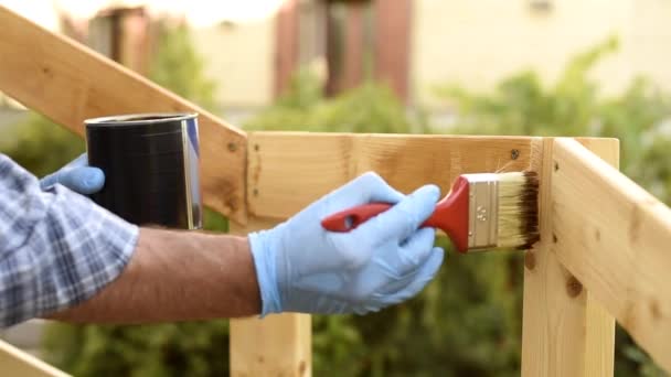 Falegname artigiano adulto con il pennello dipingere le tavole di una recinzione di legno. Lavori domestici, fallo da solo. Filmati
. - Filmati, video