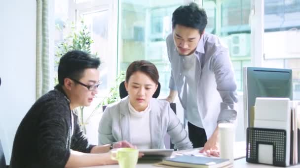 drei junge Asiaten diskutieren im Büro über Geschäfte mit Tablet-PCs - Filmmaterial, Video